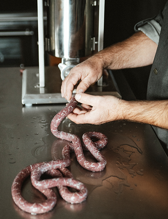 Mit einem manuellen Wurstfüller wird die Wurstmasse in den Darm gefüllt